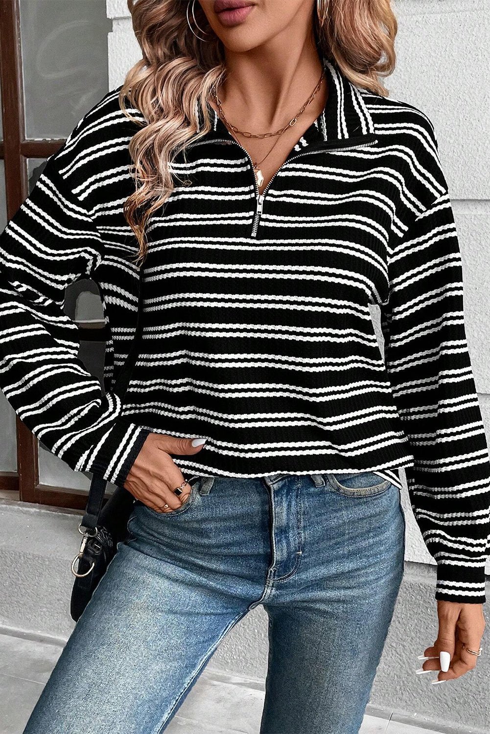 Top de manga larga con cuello y cremallera de un cuarto, con textura y rayas negras.