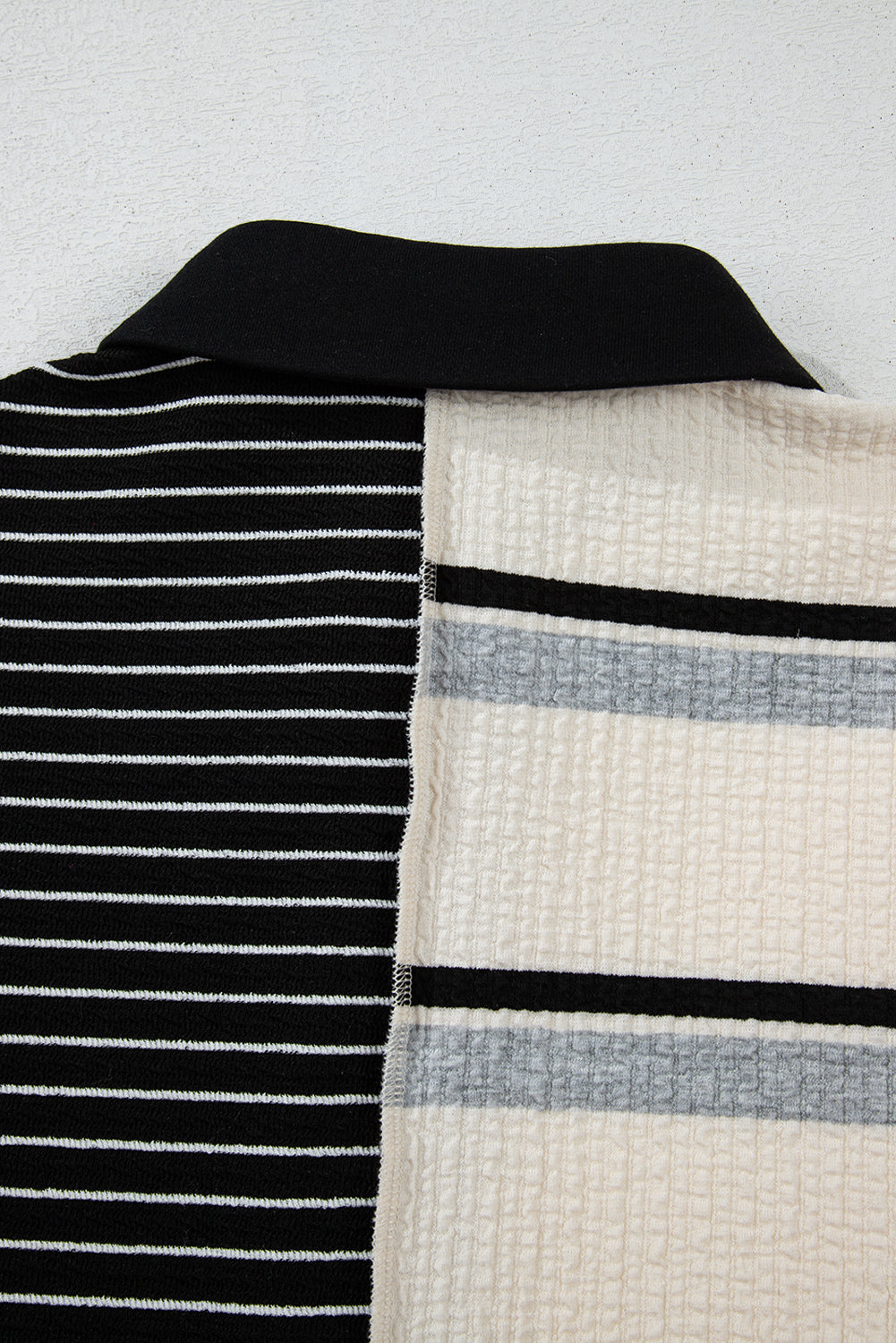 Minivestido de corte recto y manga larga con diseño de bloques de color y rayas negras, cuello Henley y tejido de punto.