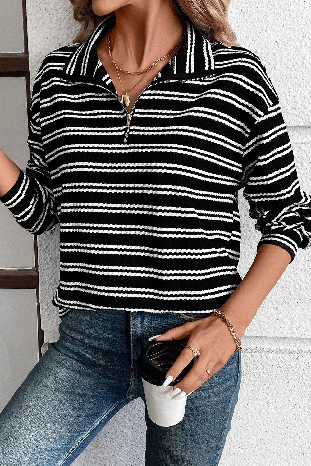 Top de manga larga con cuello y cremallera de un cuarto, con textura y rayas negras.