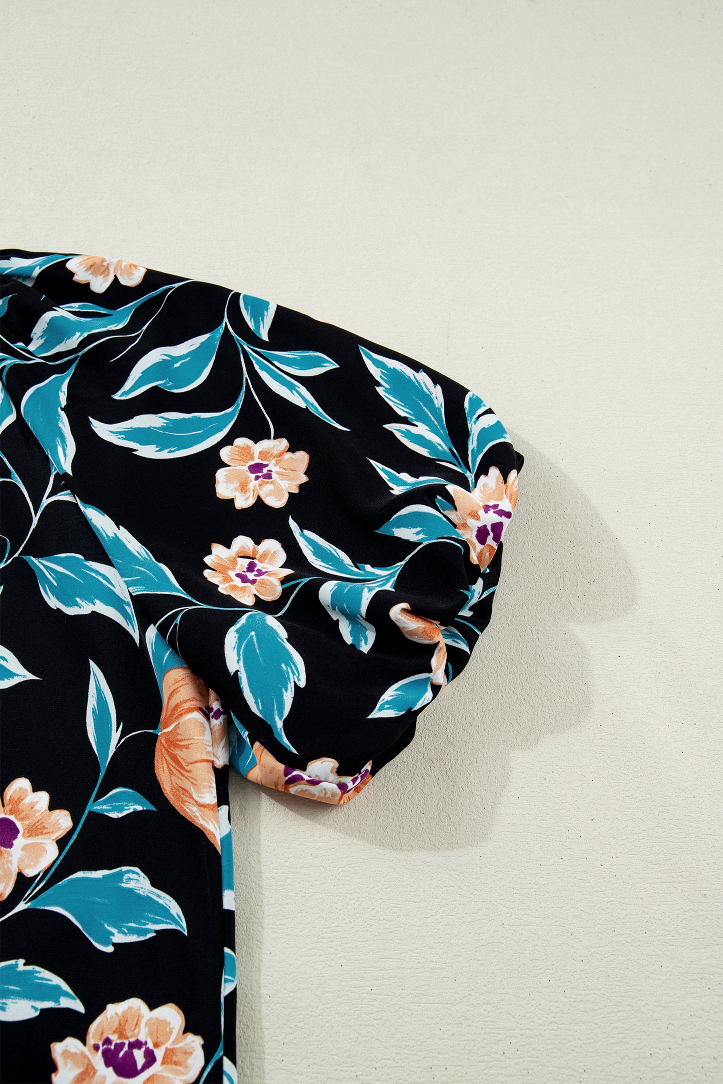 Blusa negra con estampado floral, mangas cortas abullonadas, botones y cuello con muesca