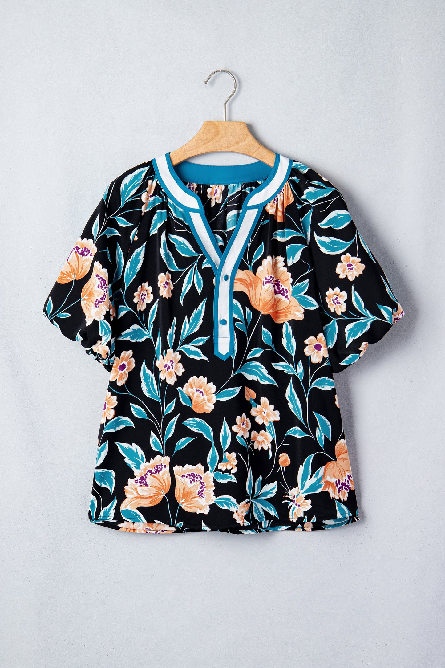 Blusa negra con estampado floral, mangas cortas abullonadas, botones y cuello con muesca