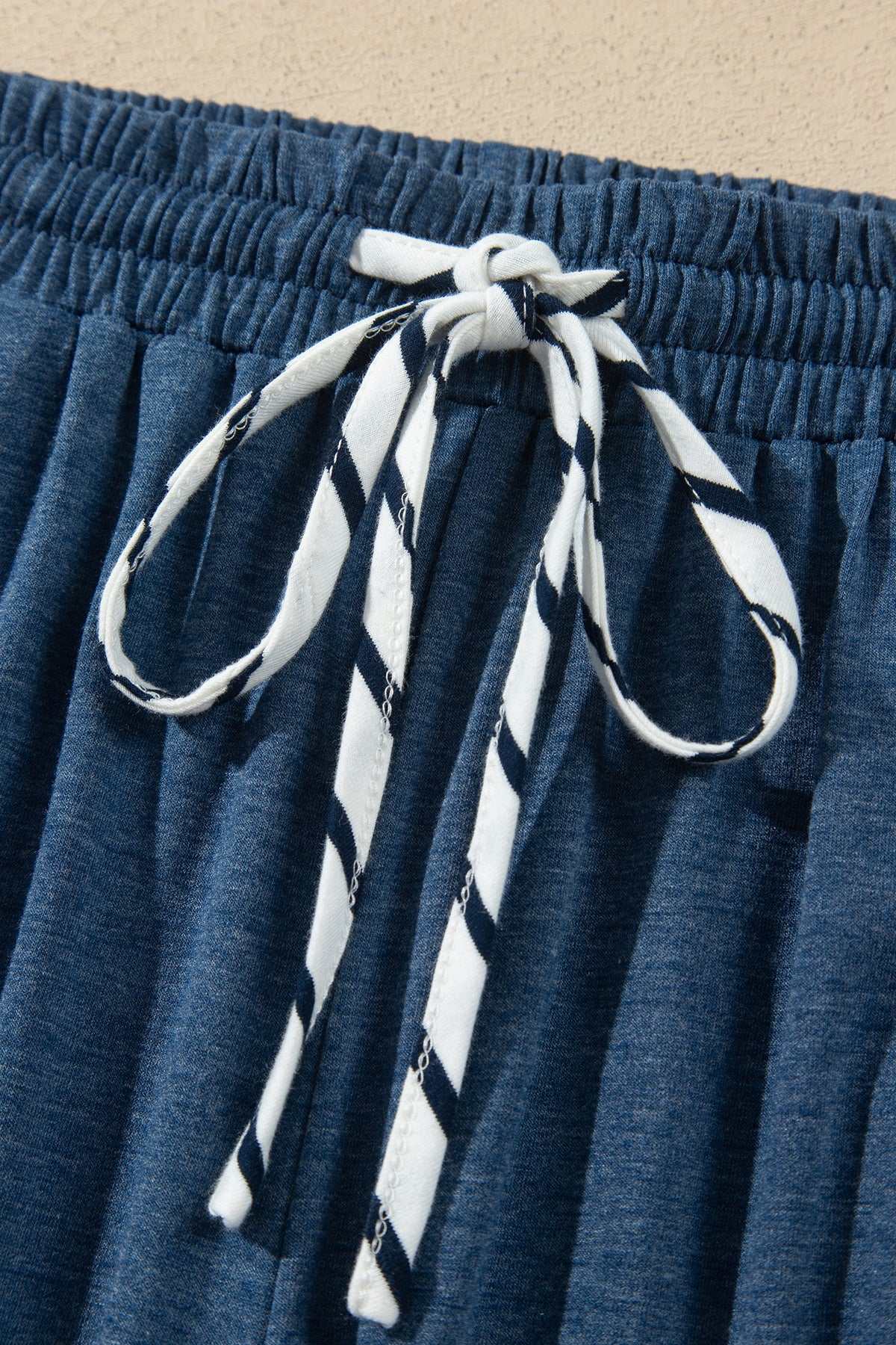 Conjunto de 2 piezas: top de rayas azules con cuello en V y mangas con volantes en contraste, y pantalón con cordón ajustable.