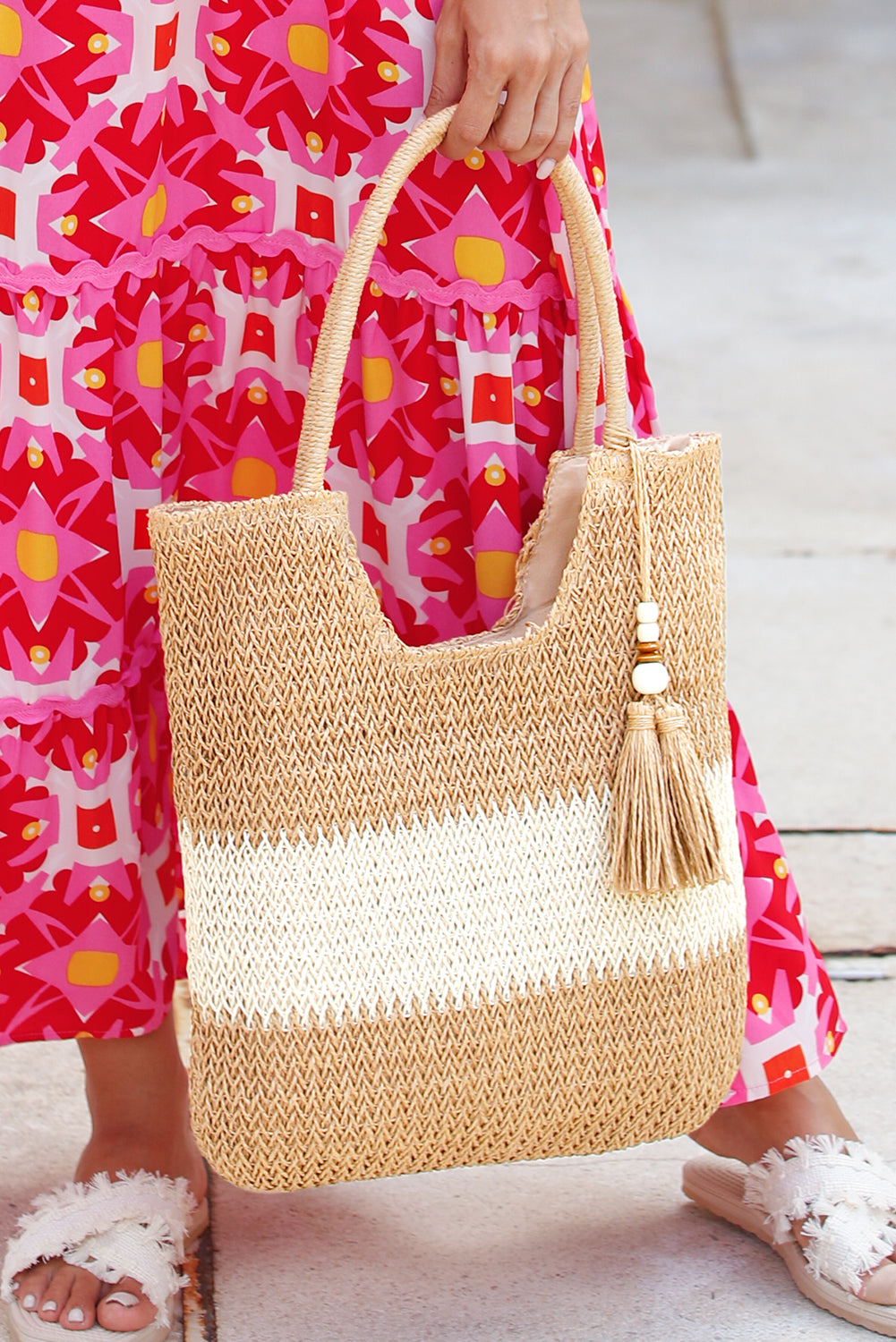 Bolso tote de paja trenzada en color castaño con diseño de bloques de color y detalle de borlas.
