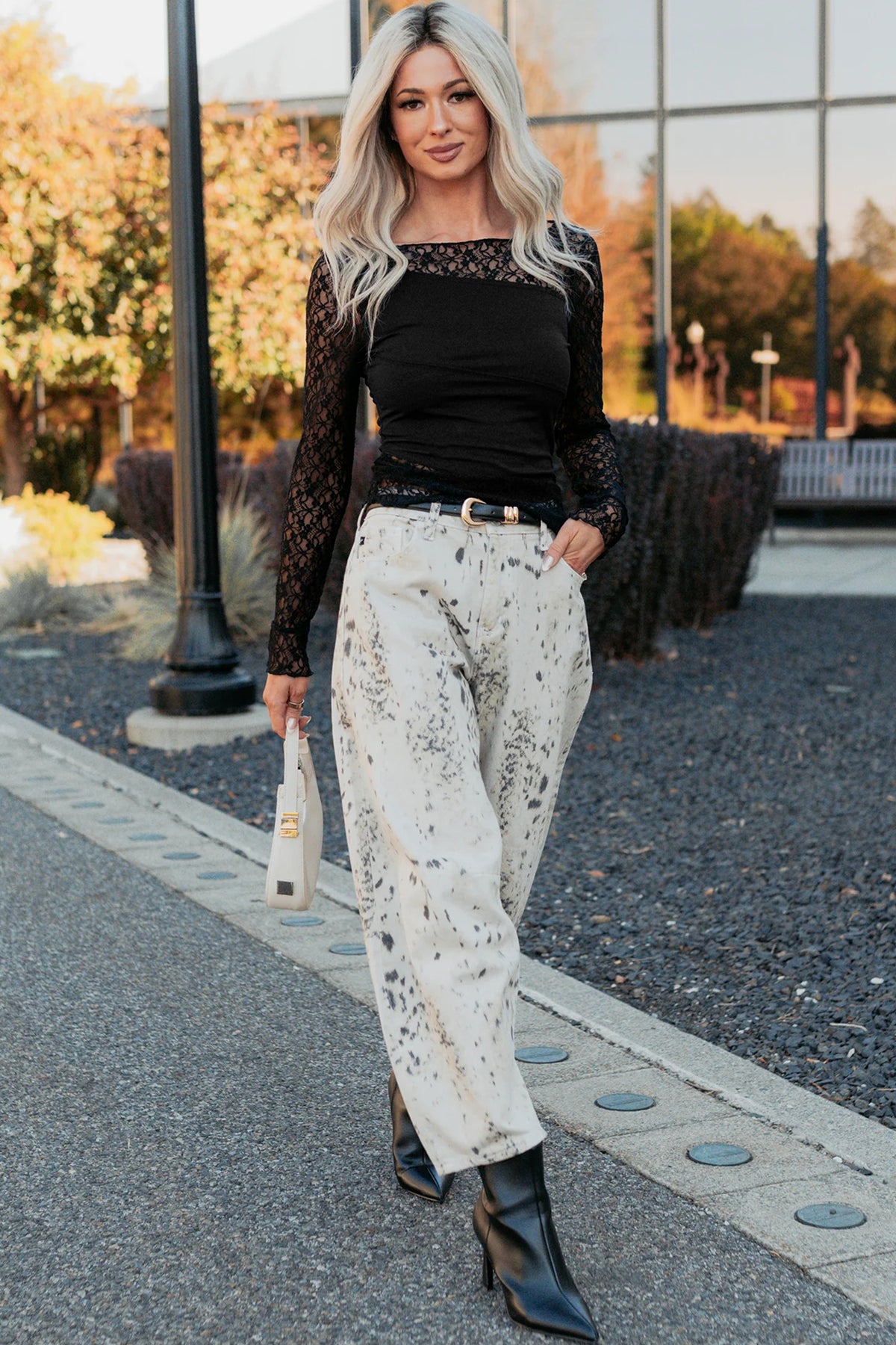 Top negro asimétrico con paneles transparentes y encaje floral en patchwork, manga larga.