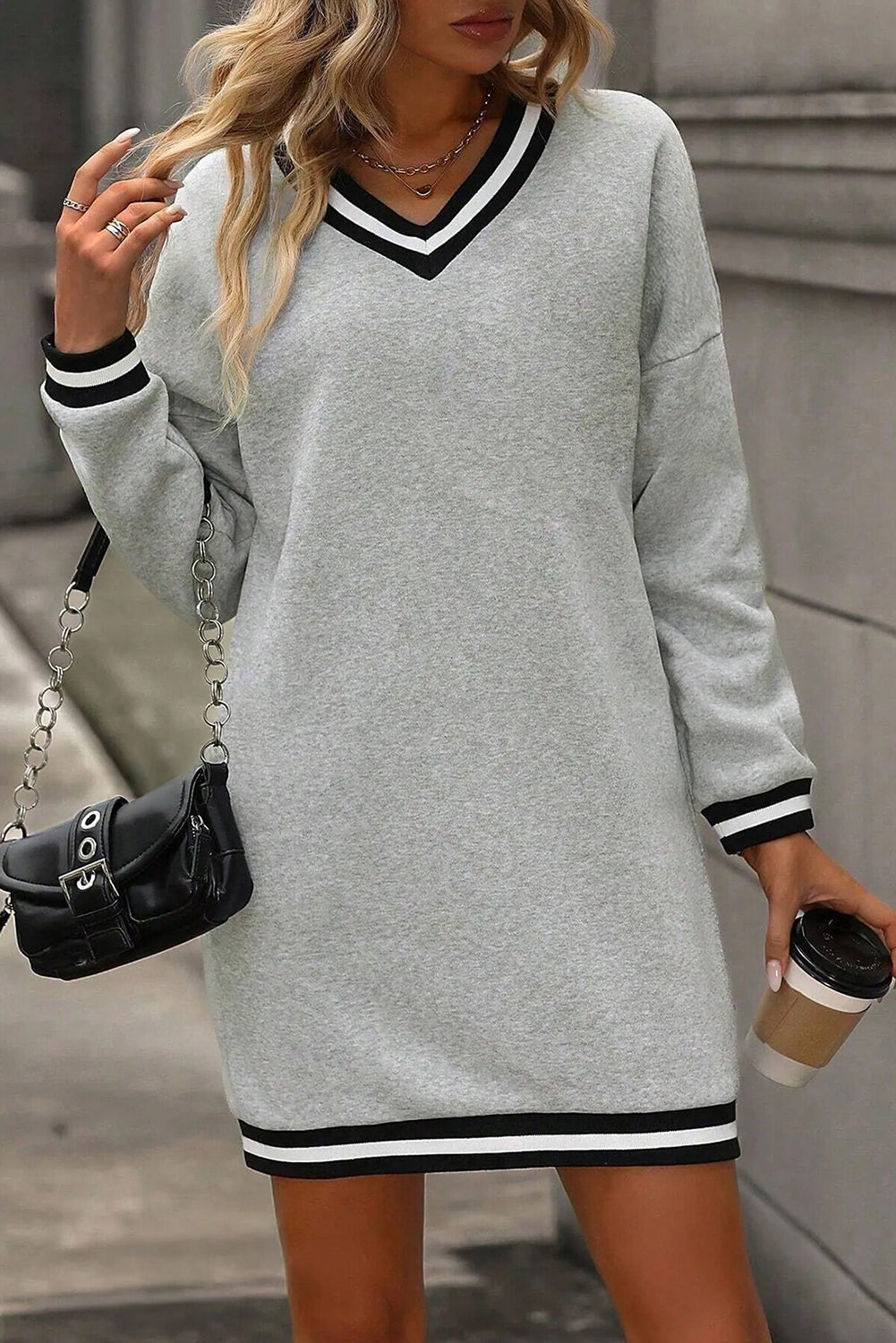 Vestido tipo camiseta de estilo preppy, manga larga y cuello en V, en gris claro con ribetes a rayas.