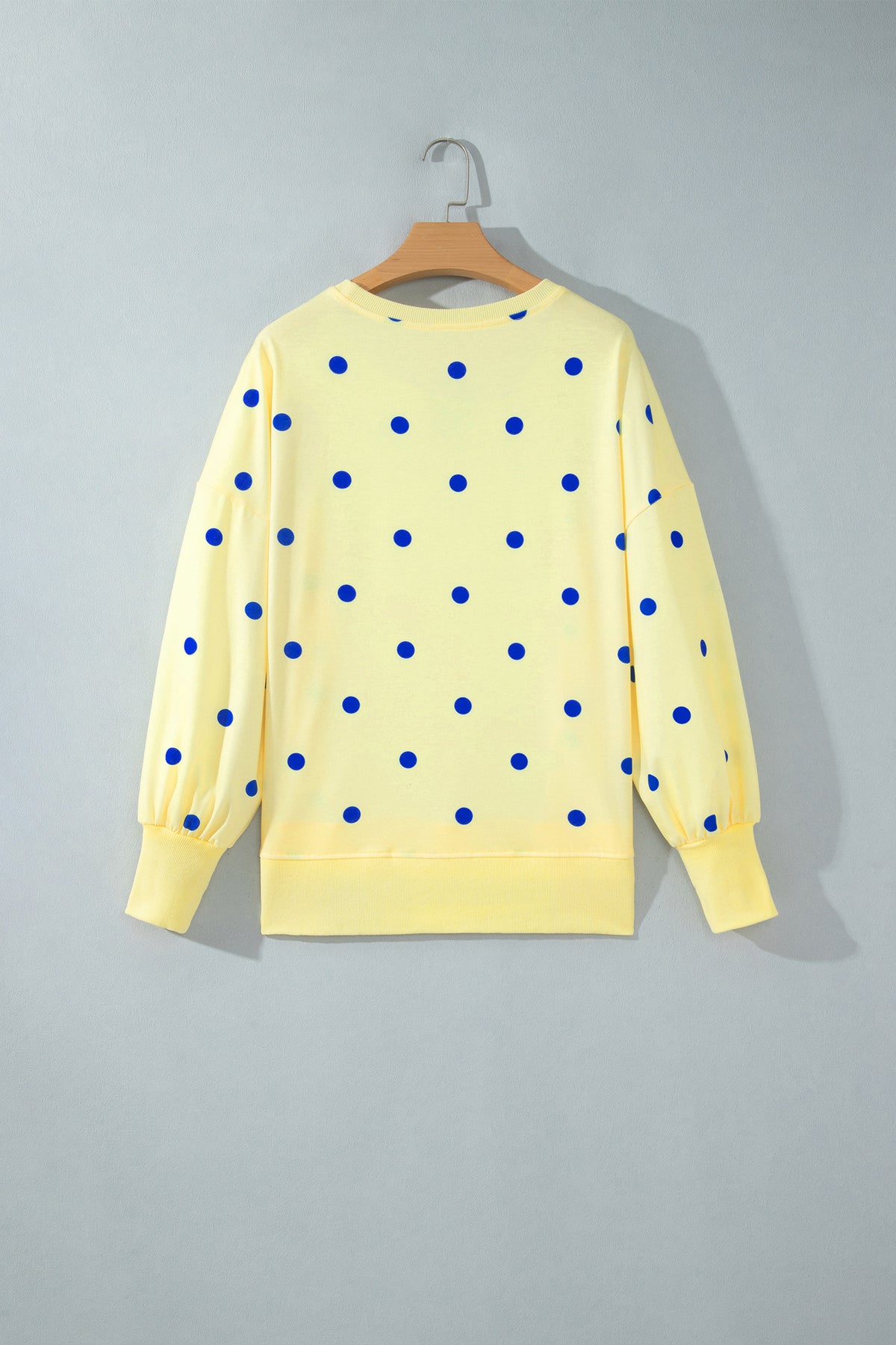 Blusa tipo suéter amarilla de manga larga y corte holgado, con estampado de lunares y bajo con aberturas laterales.
