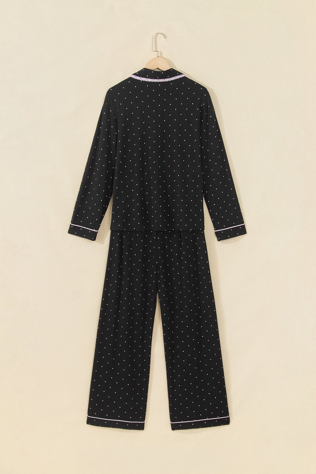 Conjunto de pijama de dos piezas: camisa de manga larga negra con lunares y detalles de encaje, y pantalón.