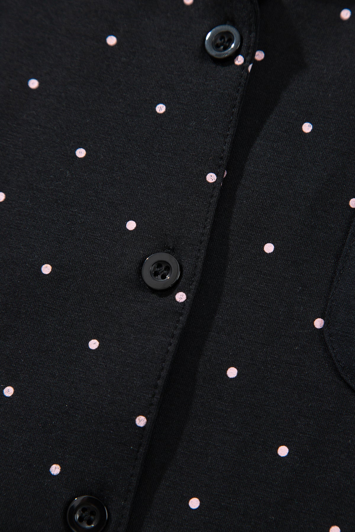 Conjunto de pijama de dos piezas: camisa de manga larga negra con lunares y detalles de encaje, y pantalón.