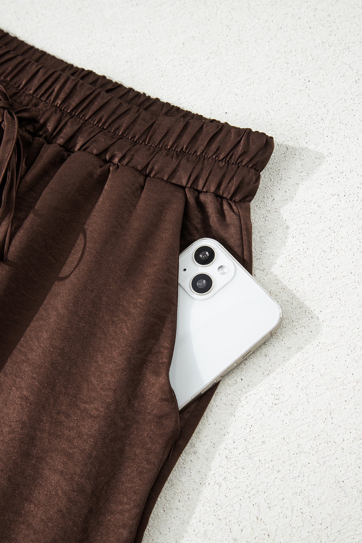 Conjunto de 2 piezas: blusa holgada de manga larga con cuello en V y detalle trenzado, y pantalón de tiro alto con cordón, en color marrón oscuro.