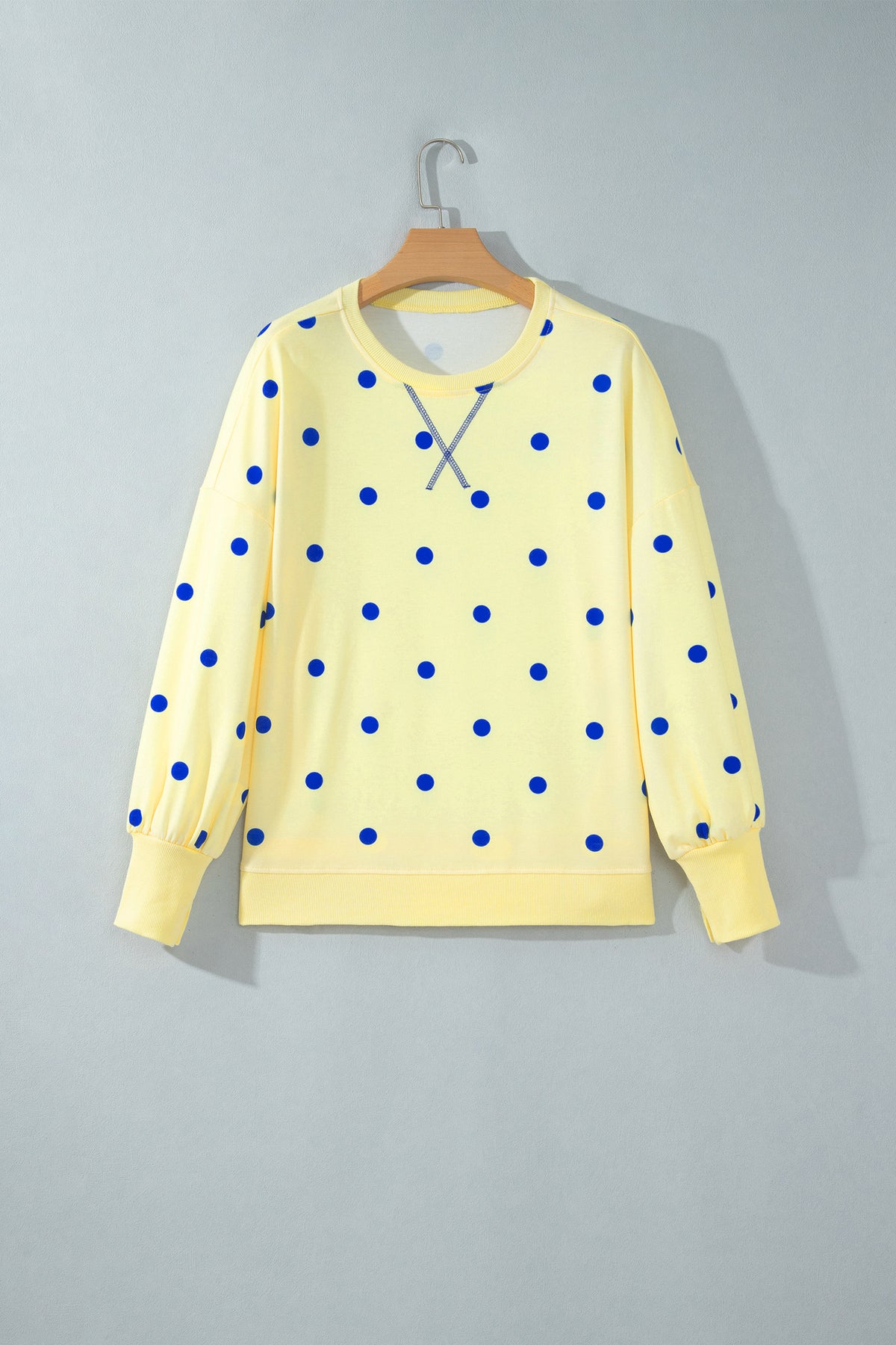 Blusa tipo suéter amarilla de manga larga y corte holgado, con estampado de lunares y bajo con aberturas laterales.