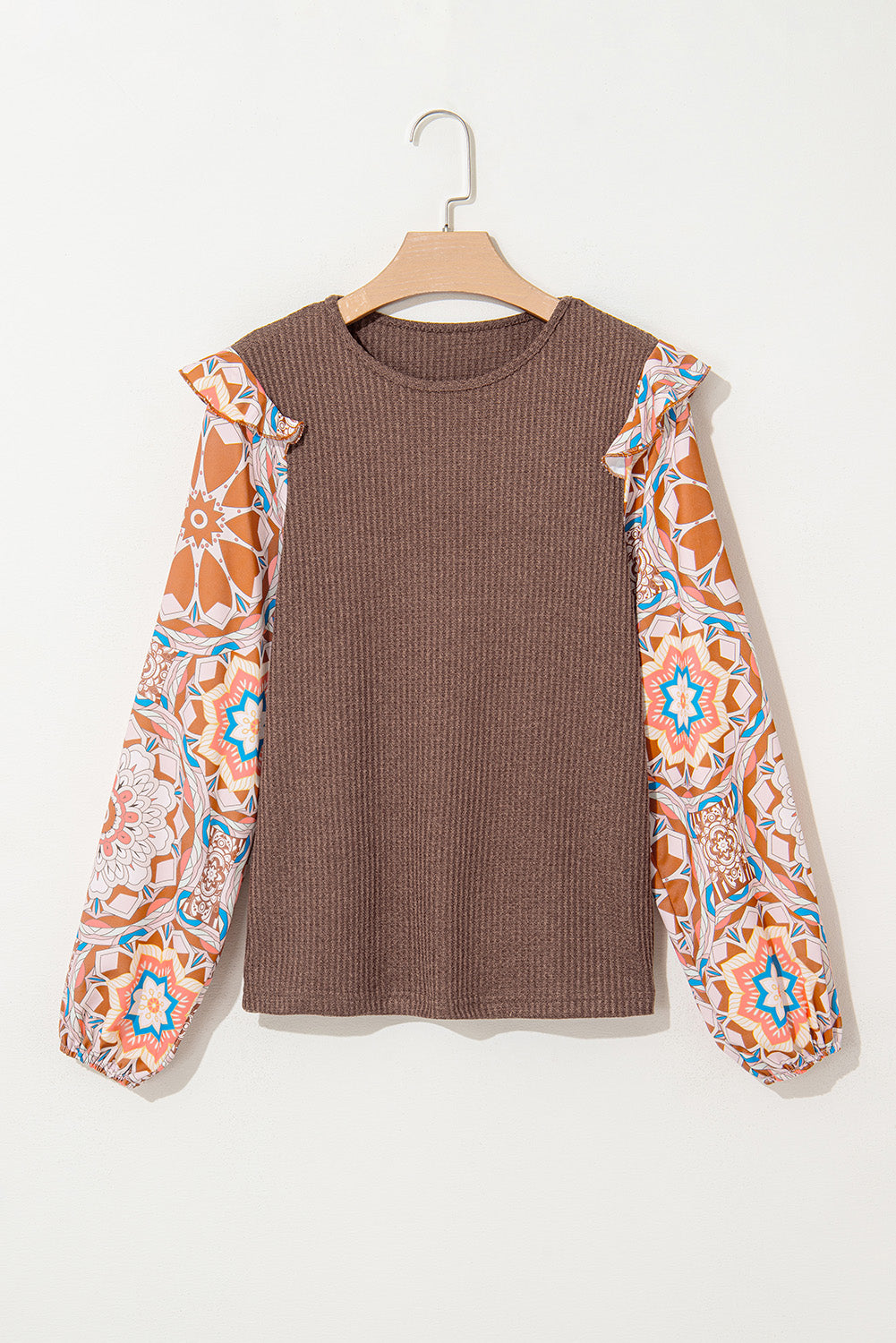 Blusa azul de punto tipo gofre con cuello redondo, diseño de paneles (patchwork), estampado floral y mangas con volantes.