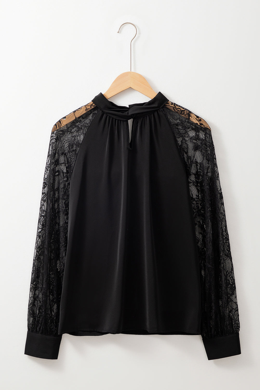 Blusa negra de encaje floral con manga raglán y abertura en el cuello