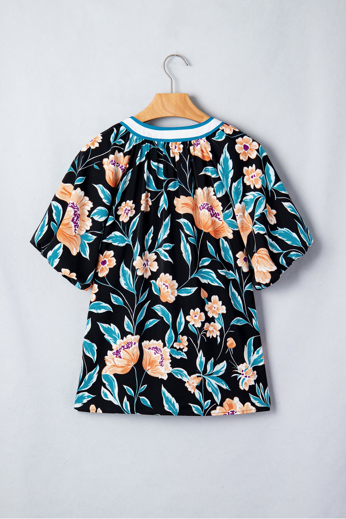 Blusa negra con estampado floral, mangas cortas abullonadas, botones y cuello con muesca