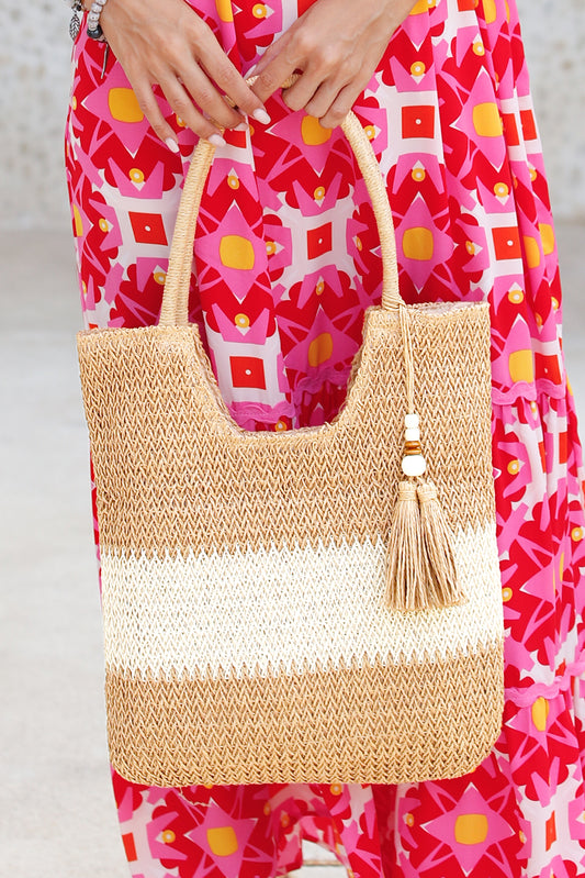 Bolso tote de paja trenzada en color castaño con diseño de bloques de color y detalle de borlas.