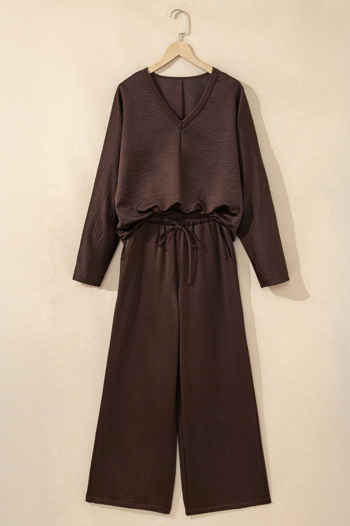 Conjunto de 2 piezas: blusa holgada de manga larga con cuello en V y detalle trenzado, y pantalón de tiro alto con cordón, en color marrón oscuro.