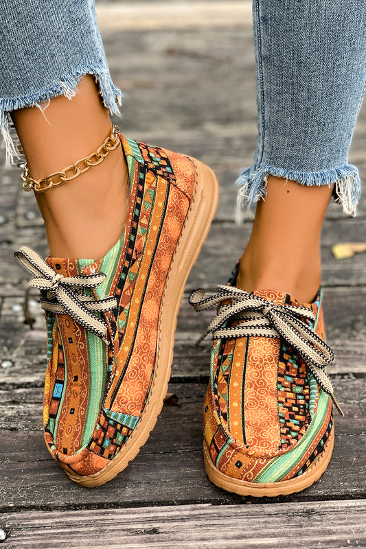 Mocasines cómodos color mostaza con estampado artístico de estilo étnico y detalle de cordones.