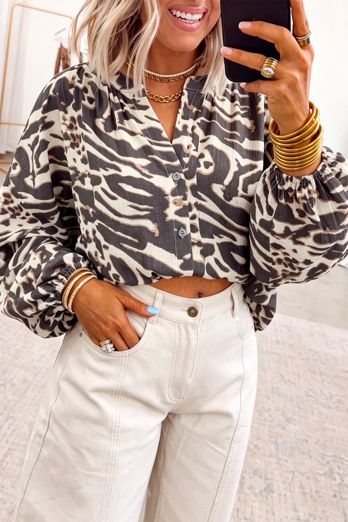 Camisa color pergamino con estampado de leopardo, cuello en V, cierre de botones y mangas abullonadas.