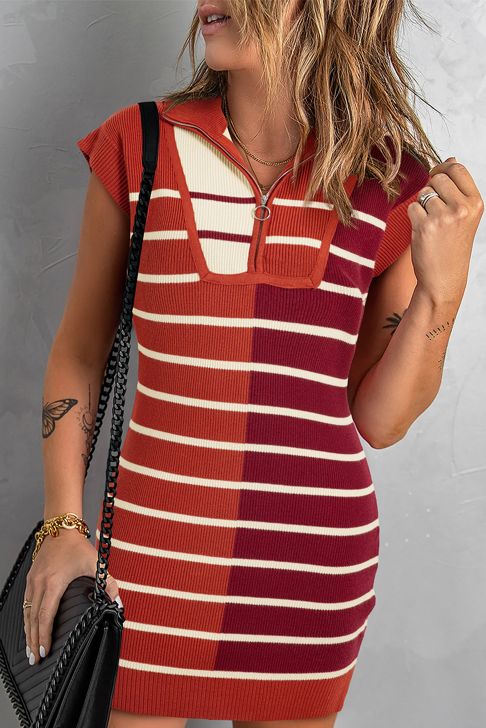 Vestido tipo suéter de manga corta con bloques de color y rayas negras, y cuello con cremallera parcial.