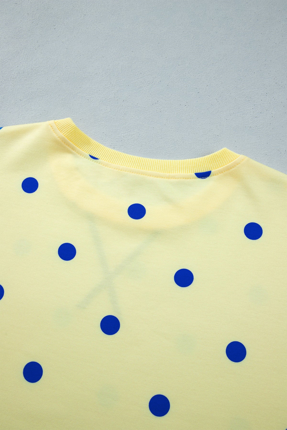 Blusa tipo suéter amarilla de manga larga y corte holgado, con estampado de lunares y bajo con aberturas laterales.