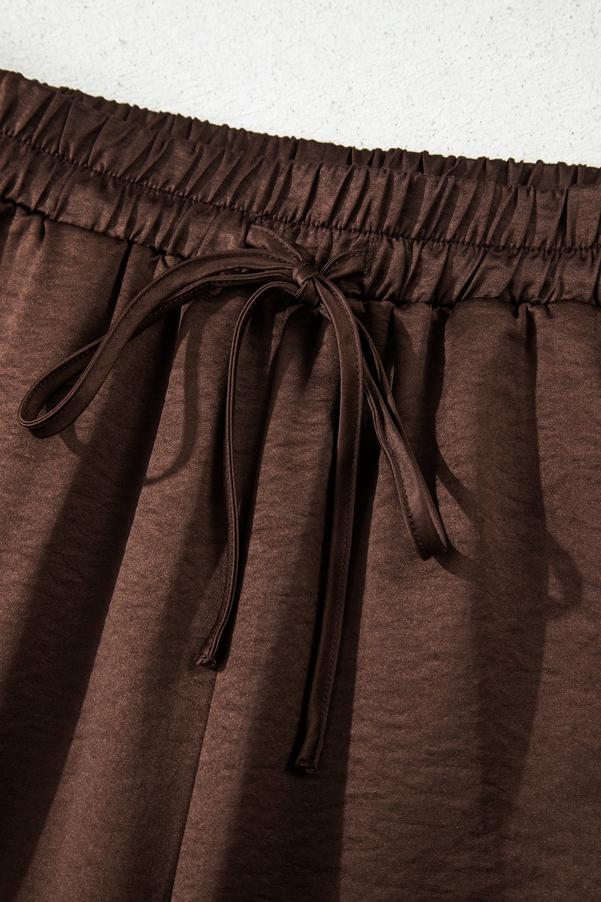 Conjunto de 2 piezas: blusa holgada de manga larga con cuello en V y detalle trenzado, y pantalón de tiro alto con cordón, en color marrón oscuro.