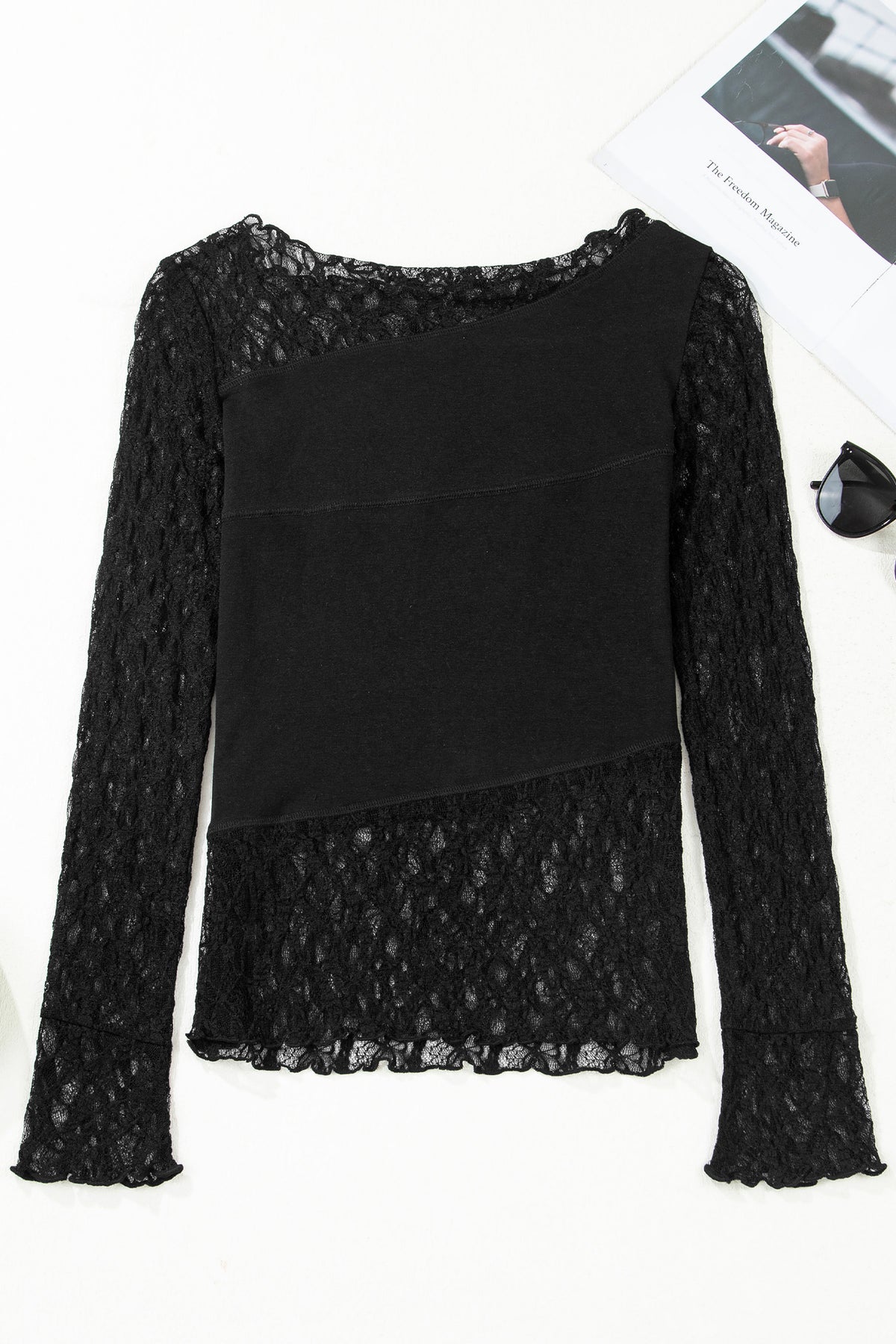 Top negro asimétrico con paneles transparentes y encaje floral en patchwork, manga larga.