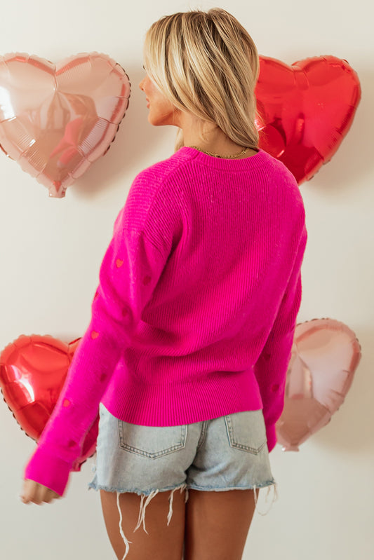 Suéter rojo rosa con cuello redondo, hombros caídos y diseño de corazón.