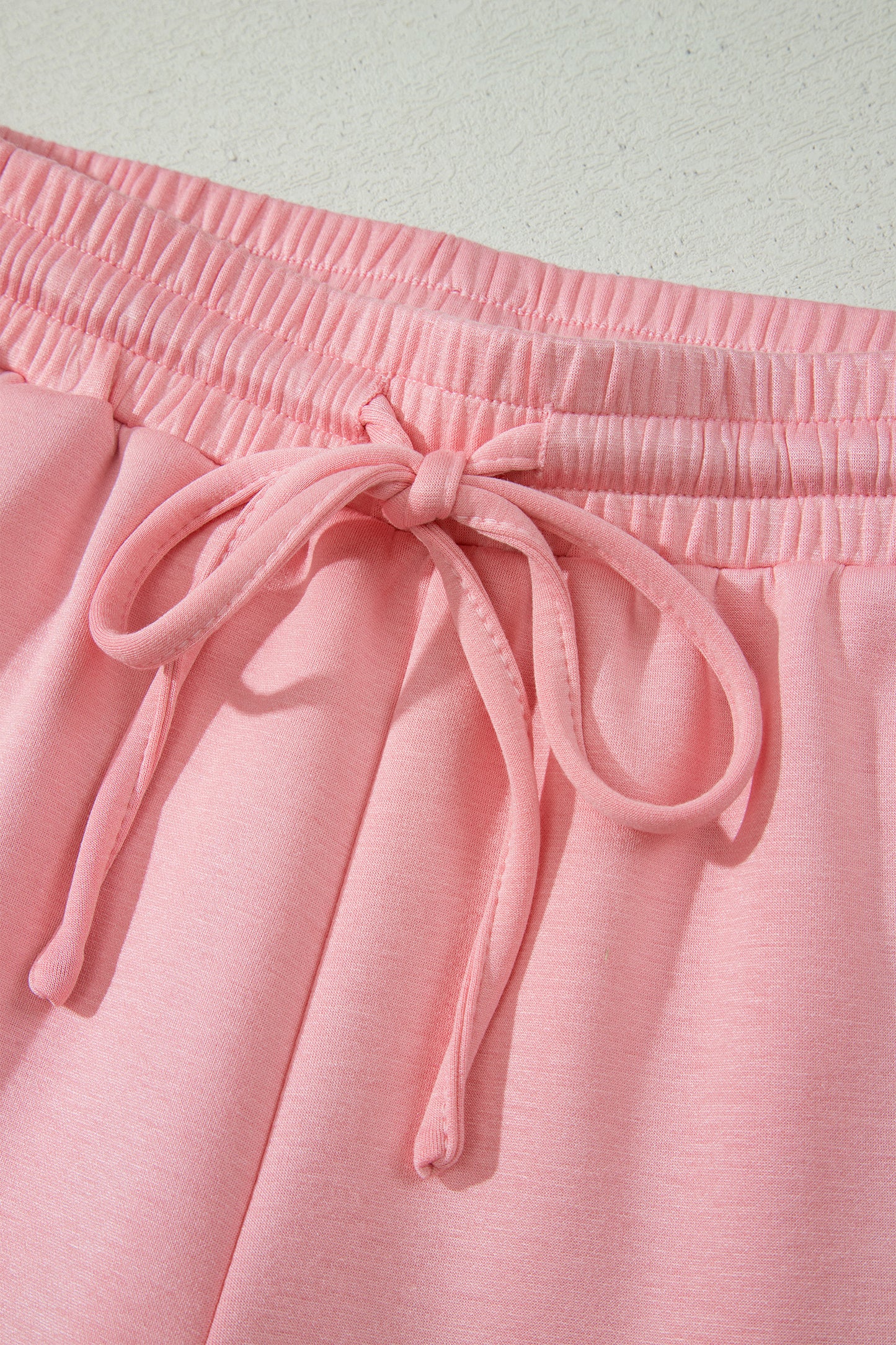 Conjunto de top tipo dolman oversize rosa con cuello en V festoneado y cordón ajustable