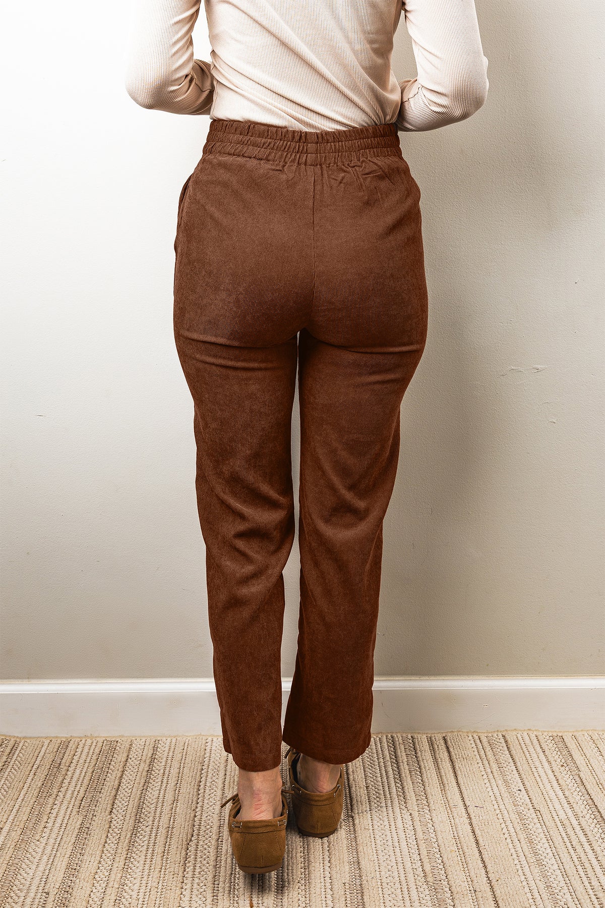 Pantalones de pana color café, de corte recto, largo al tobillo y cintura elástica.