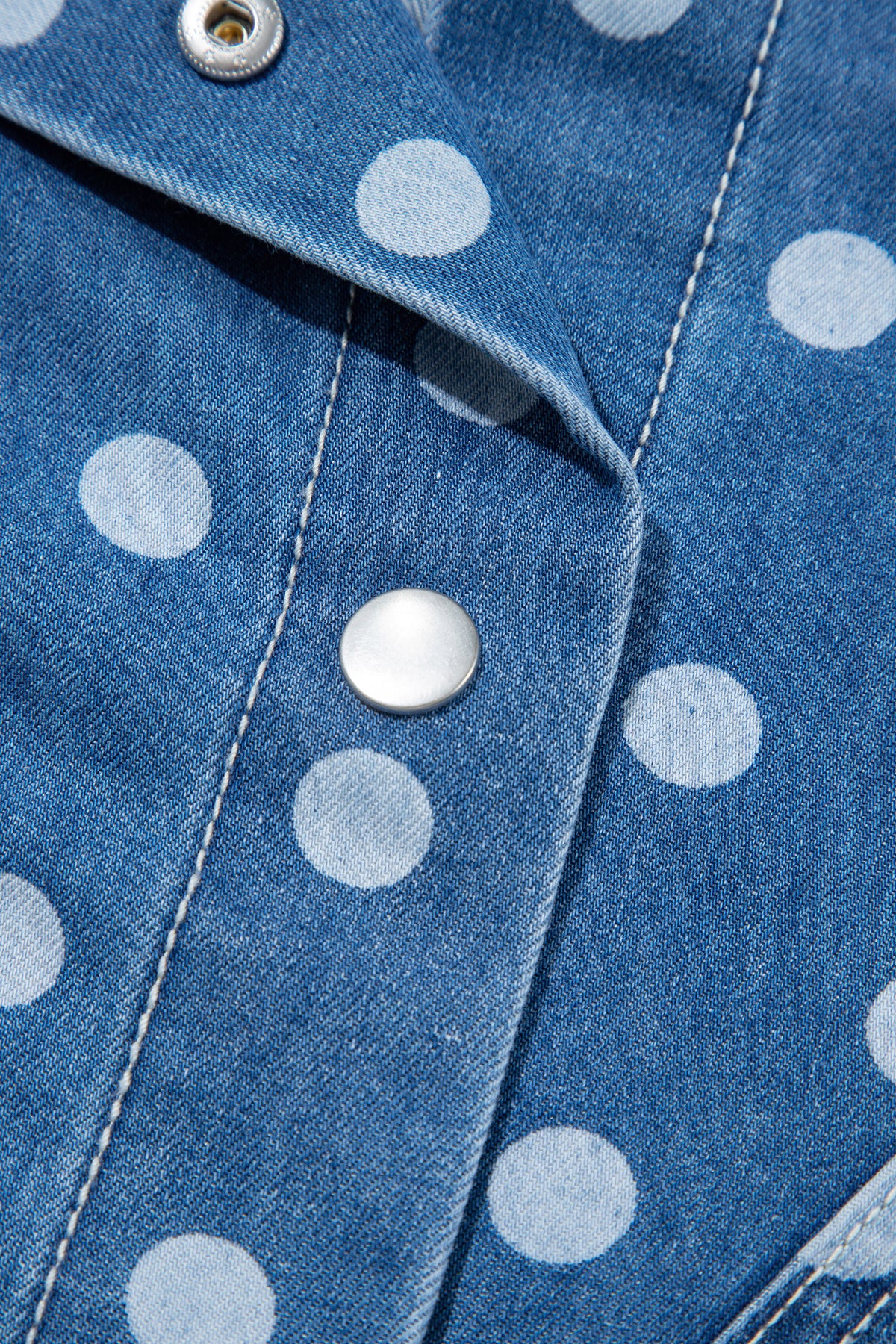 Chaqueta tipo túnica de mezclilla, corte recto, con cuello, manga larga y estampado de lunares azules.