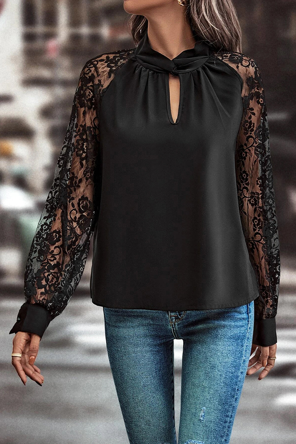 Blusa negra de encaje floral con manga raglán y abertura en el cuello