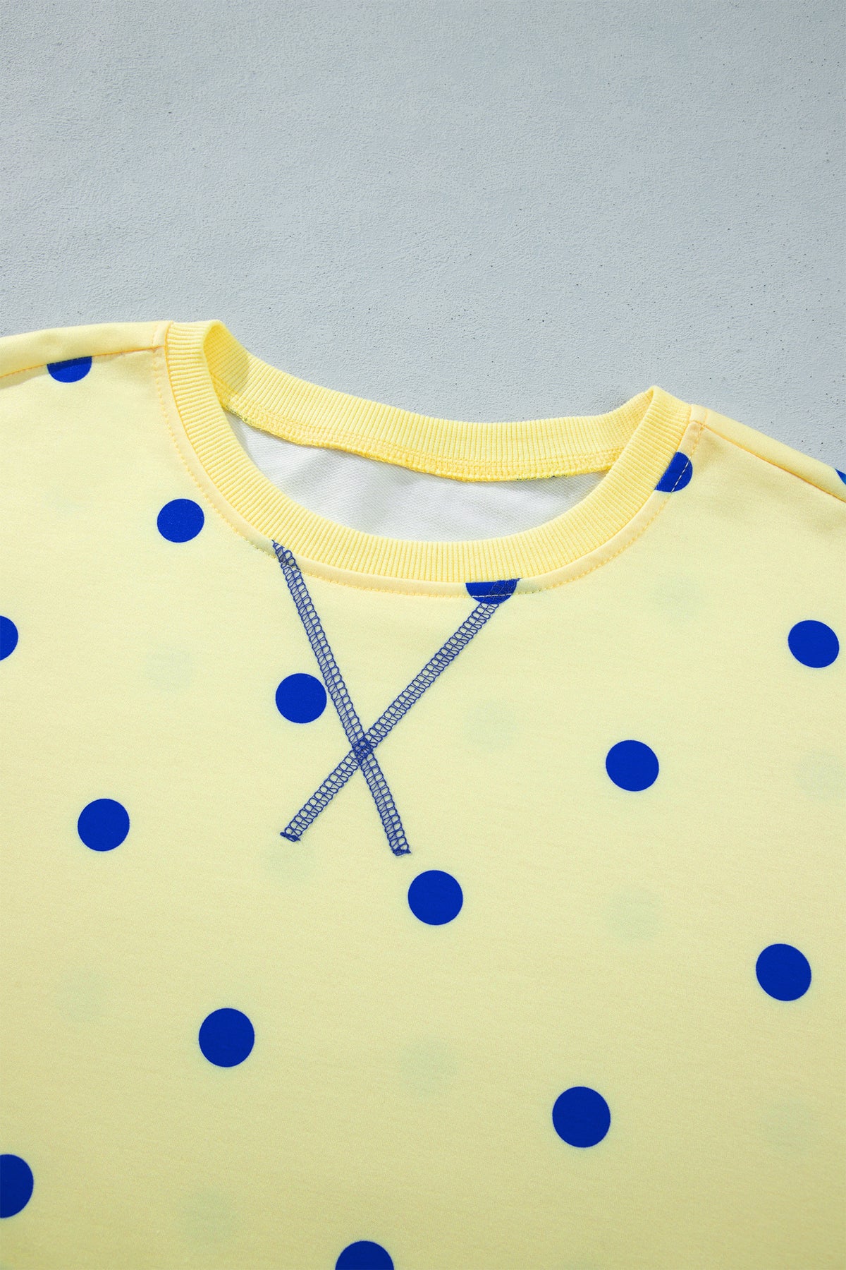 Blusa tipo suéter amarilla de manga larga y corte holgado, con estampado de lunares y bajo con aberturas laterales.