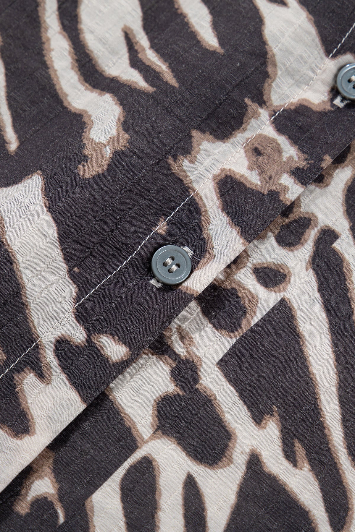 Camisa color pergamino con estampado de leopardo, cuello en V, cierre de botones y mangas abullonadas.