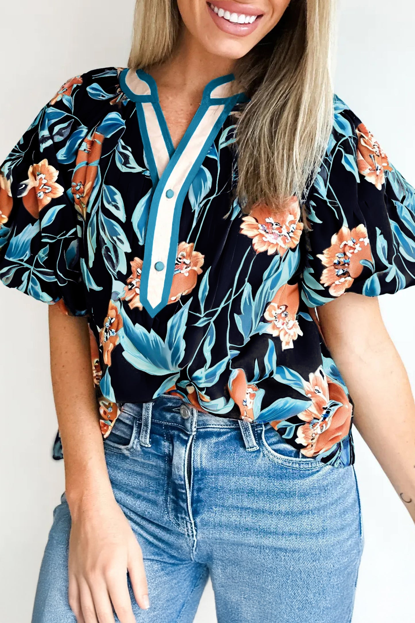 Blusa negra con estampado floral, mangas cortas abullonadas, botones y cuello con muesca