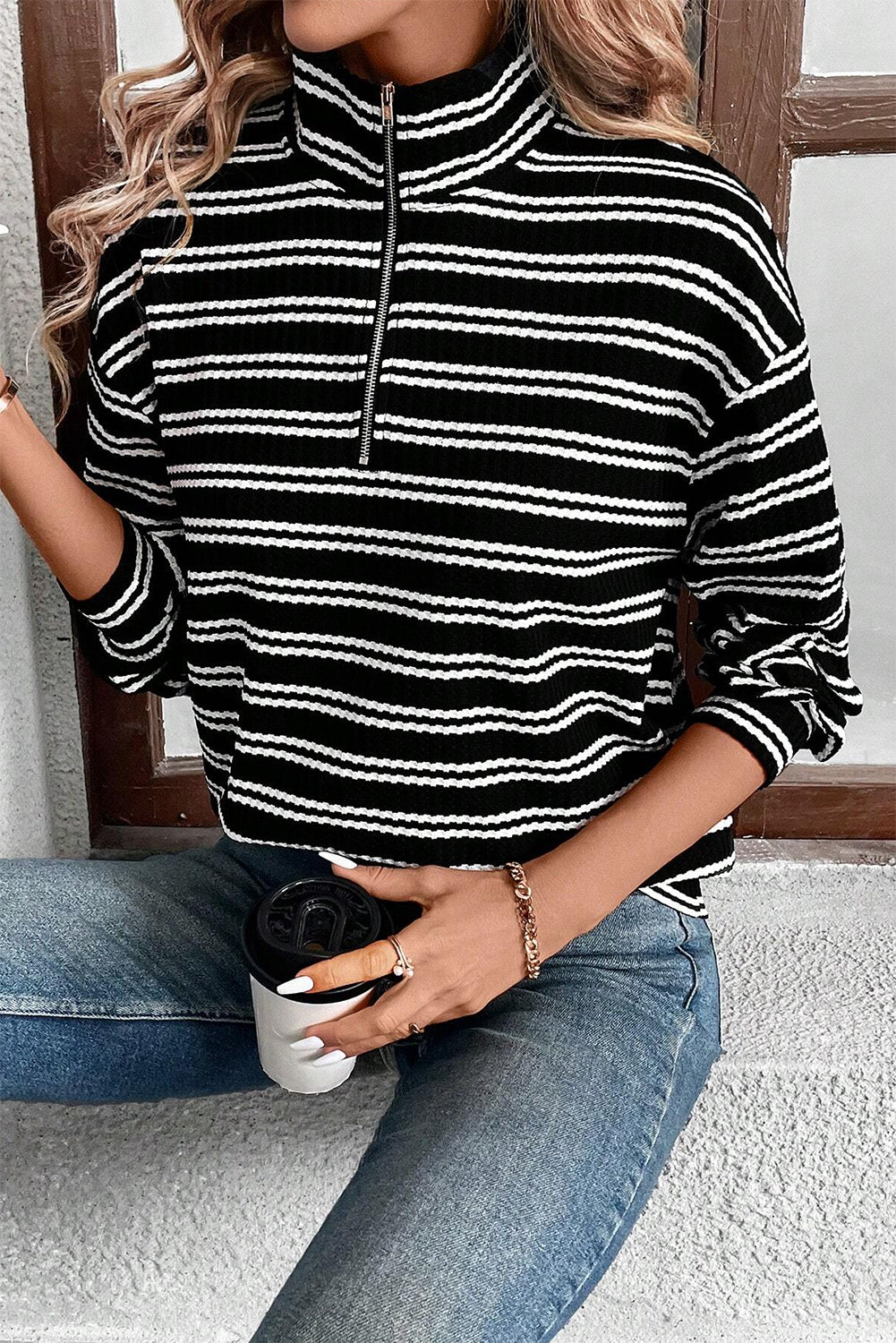 Top de manga larga con cuello y cremallera de un cuarto, con textura y rayas negras.