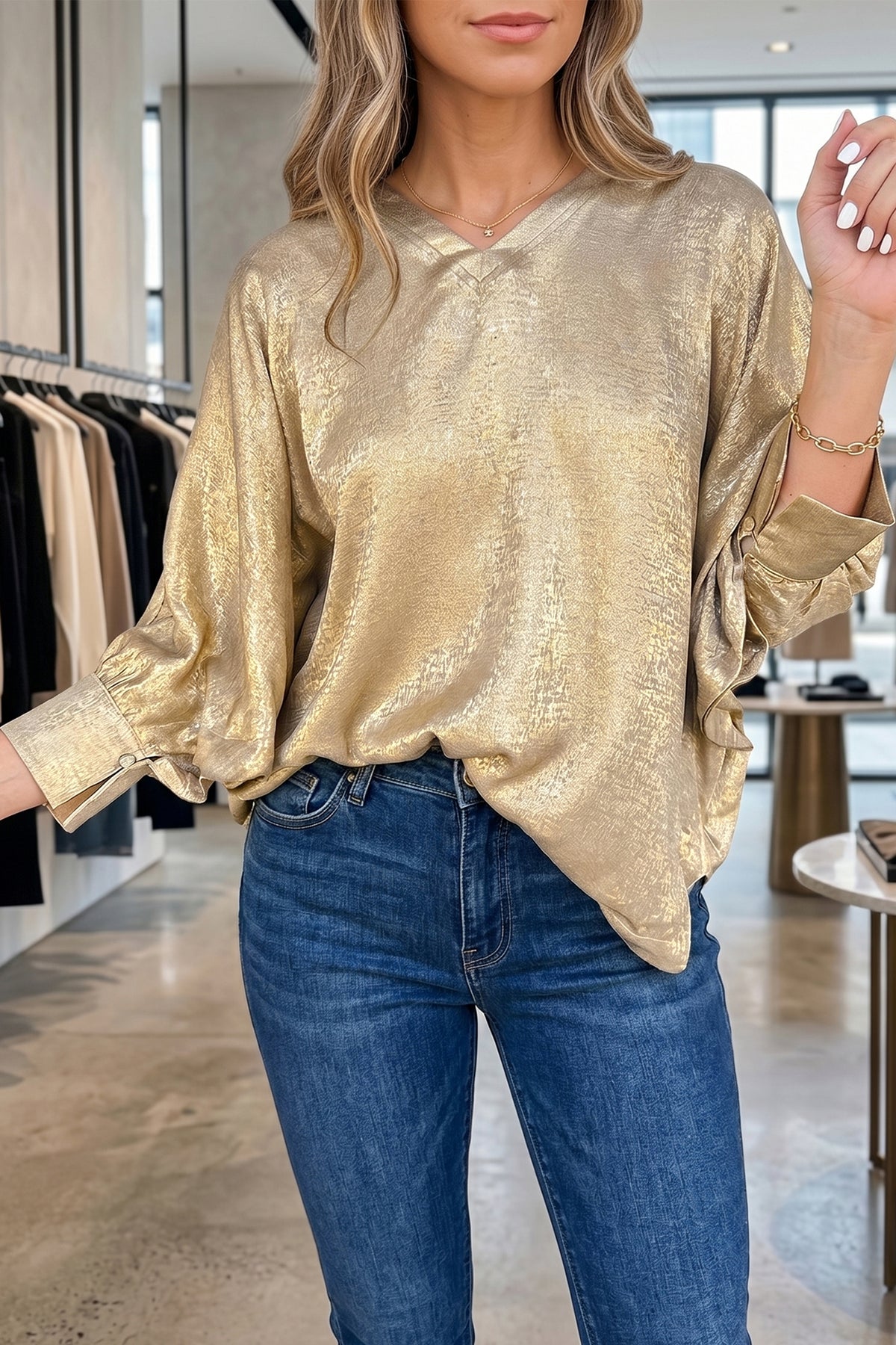 Blusa tipo dolman color pergamino metalizado con cuello en V, botones y puños en las mangas largas.