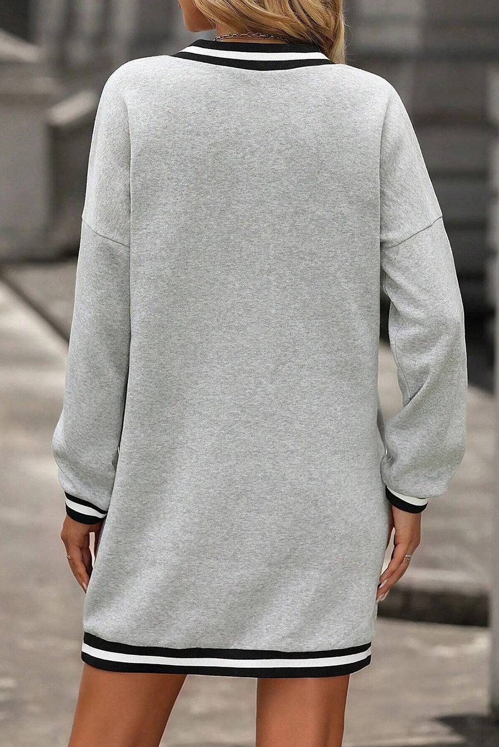 Vestido tipo camiseta de estilo preppy, manga larga y cuello en V, en gris claro con ribetes a rayas.