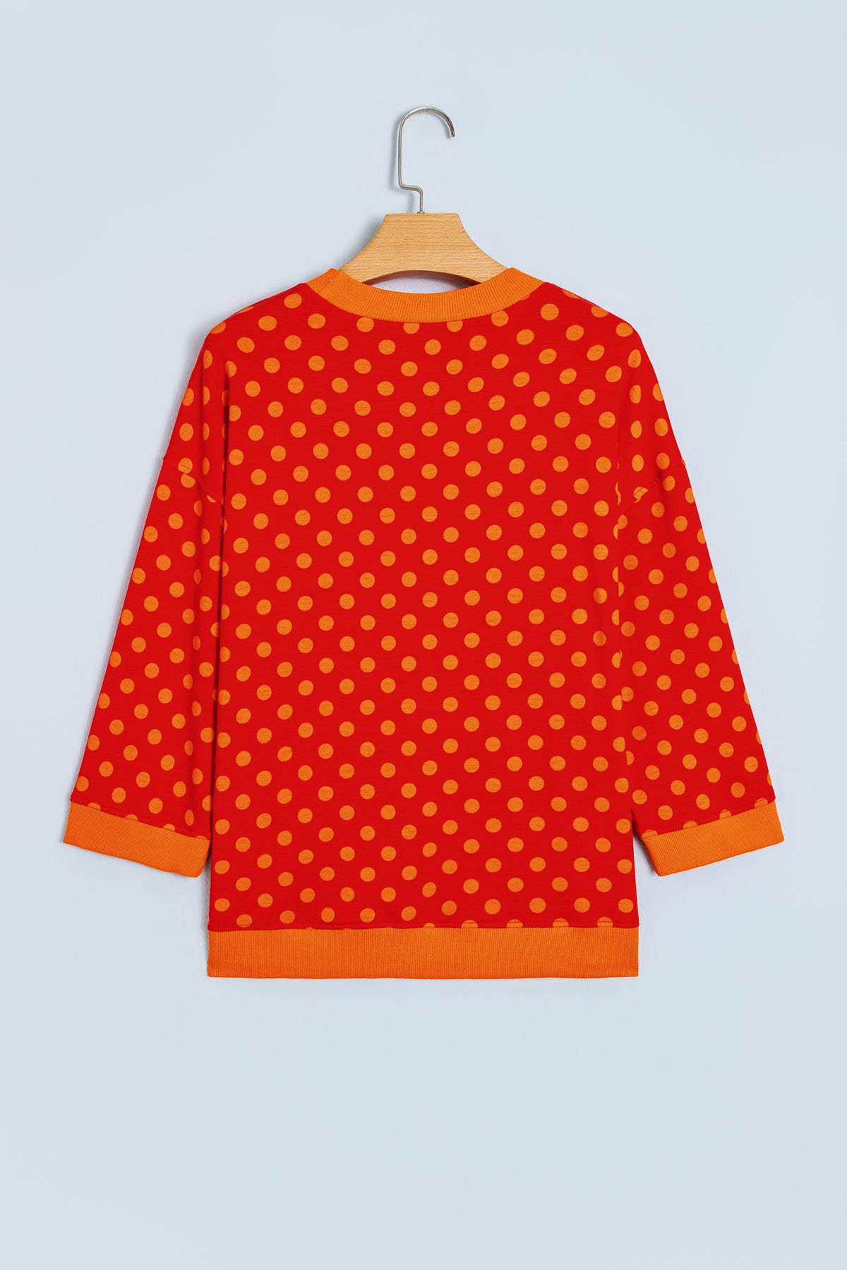Top de cuello redondo con mangas tres cuartos, estampado de lunares marrones y ribete en contraste.