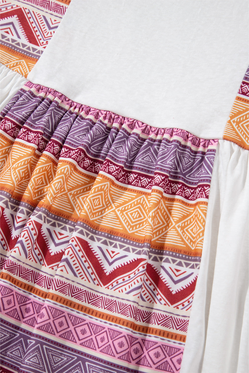 Blusa tipo túnica blanca de manga larga, corte babydoll y estilo occidental, con diseño de retazos (patchwork), estampado azteca y volantes.