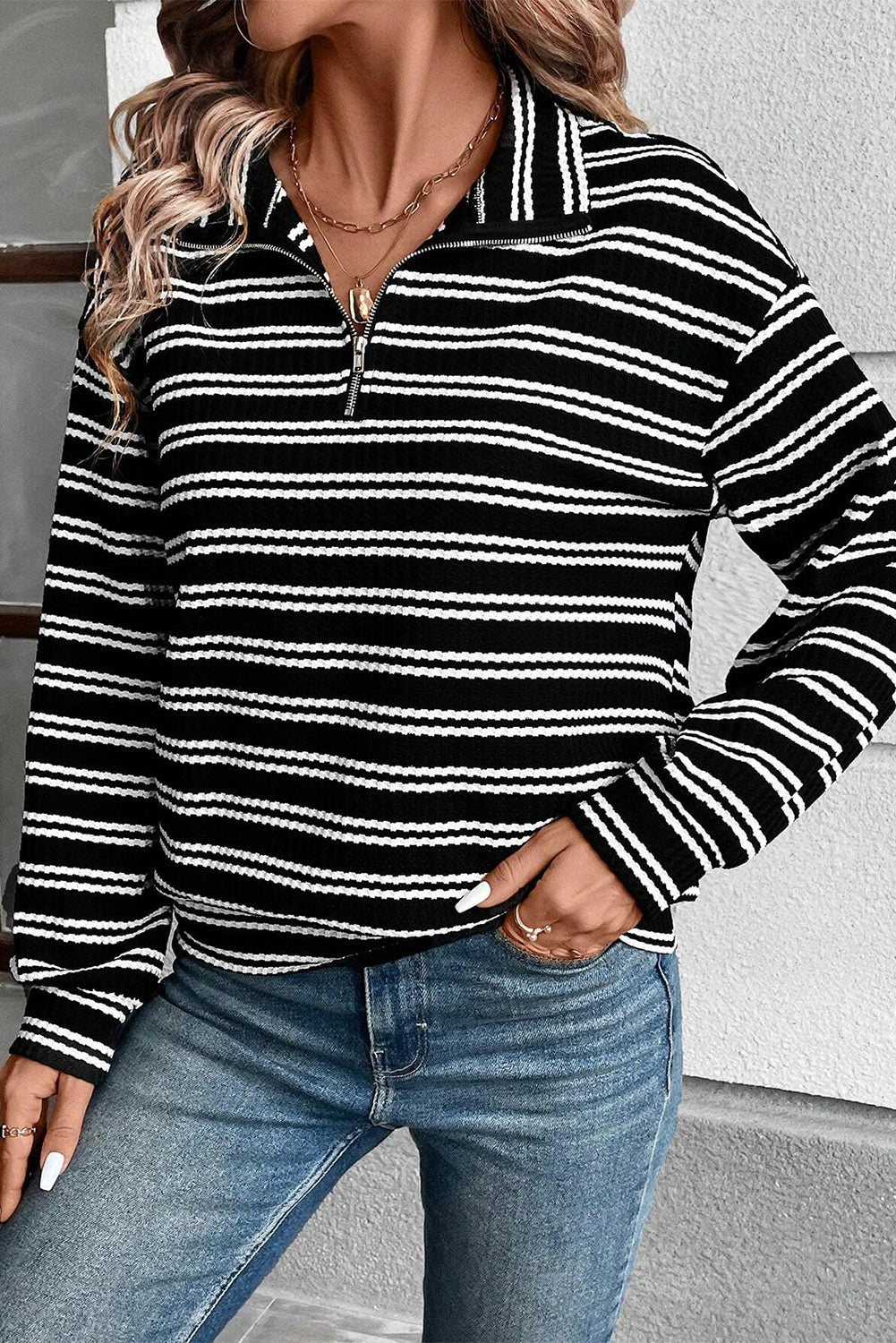 Top de manga larga con cuello y cremallera de un cuarto, con textura y rayas negras.