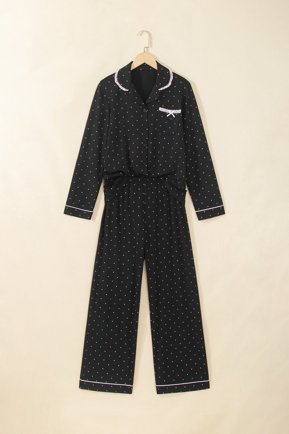 Conjunto de pijama de dos piezas: camisa de manga larga negra con lunares y detalles de encaje, y pantalón.