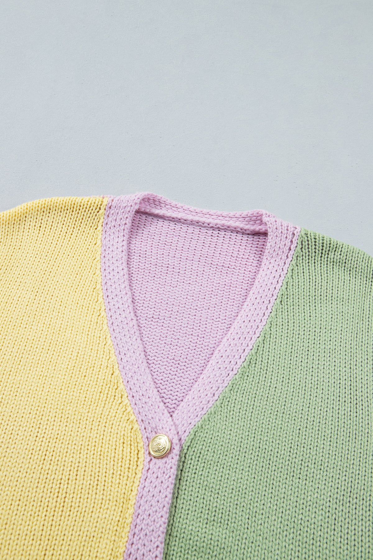 Cárdigan de punto amarillo con cuello en V, hombros caídos, diseño de paneles y lavado estándar.