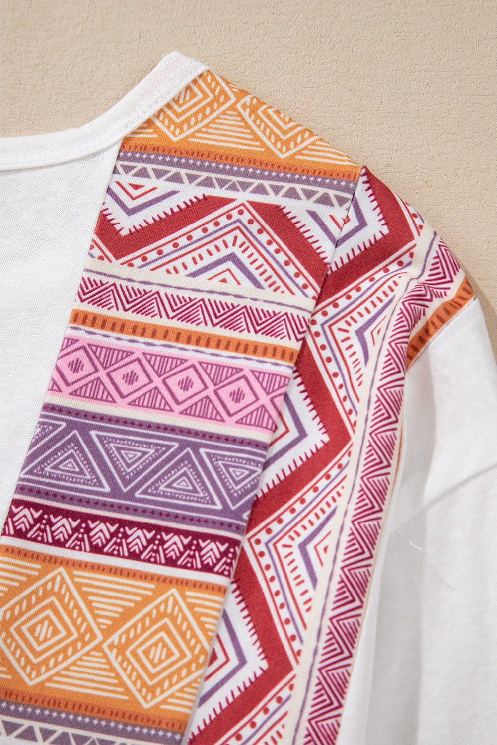Blusa tipo túnica blanca de manga larga, corte babydoll y estilo occidental, con diseño de retazos (patchwork), estampado azteca y volantes.