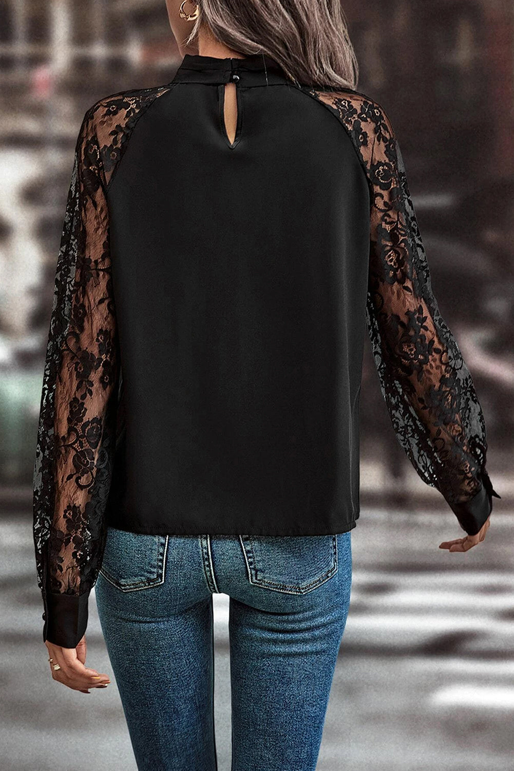 Blusa negra de encaje floral con manga raglán y abertura en el cuello