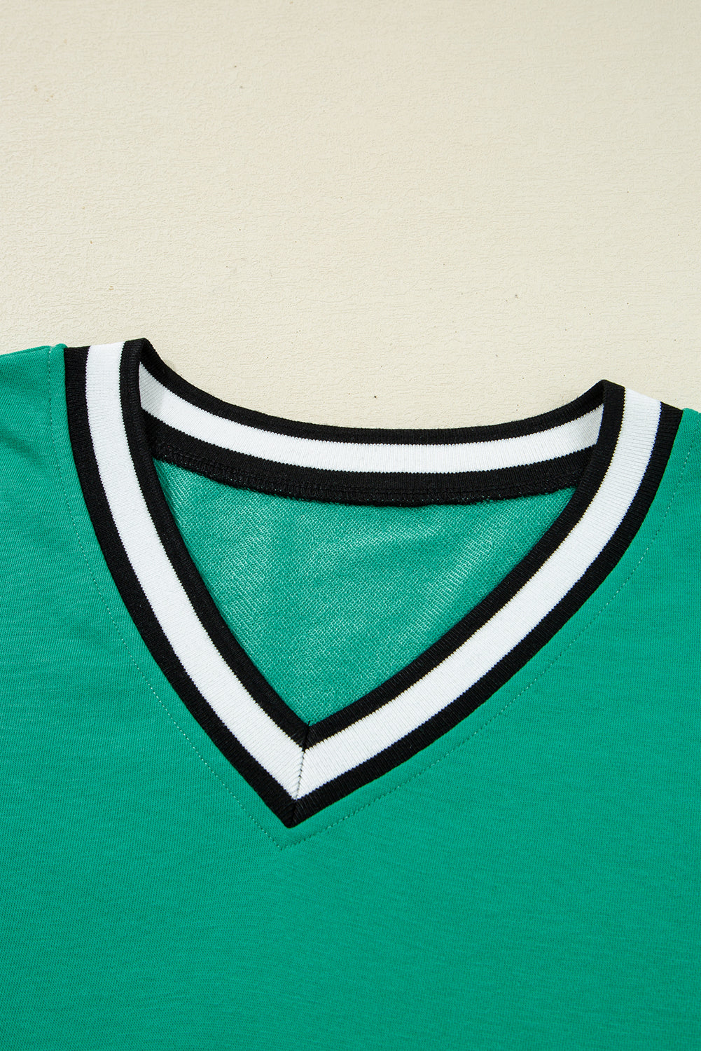 Vestido tipo camiseta de manga larga y cuello en V, color verde menta, estilo universitario con rayas en contraste y bolsillos.