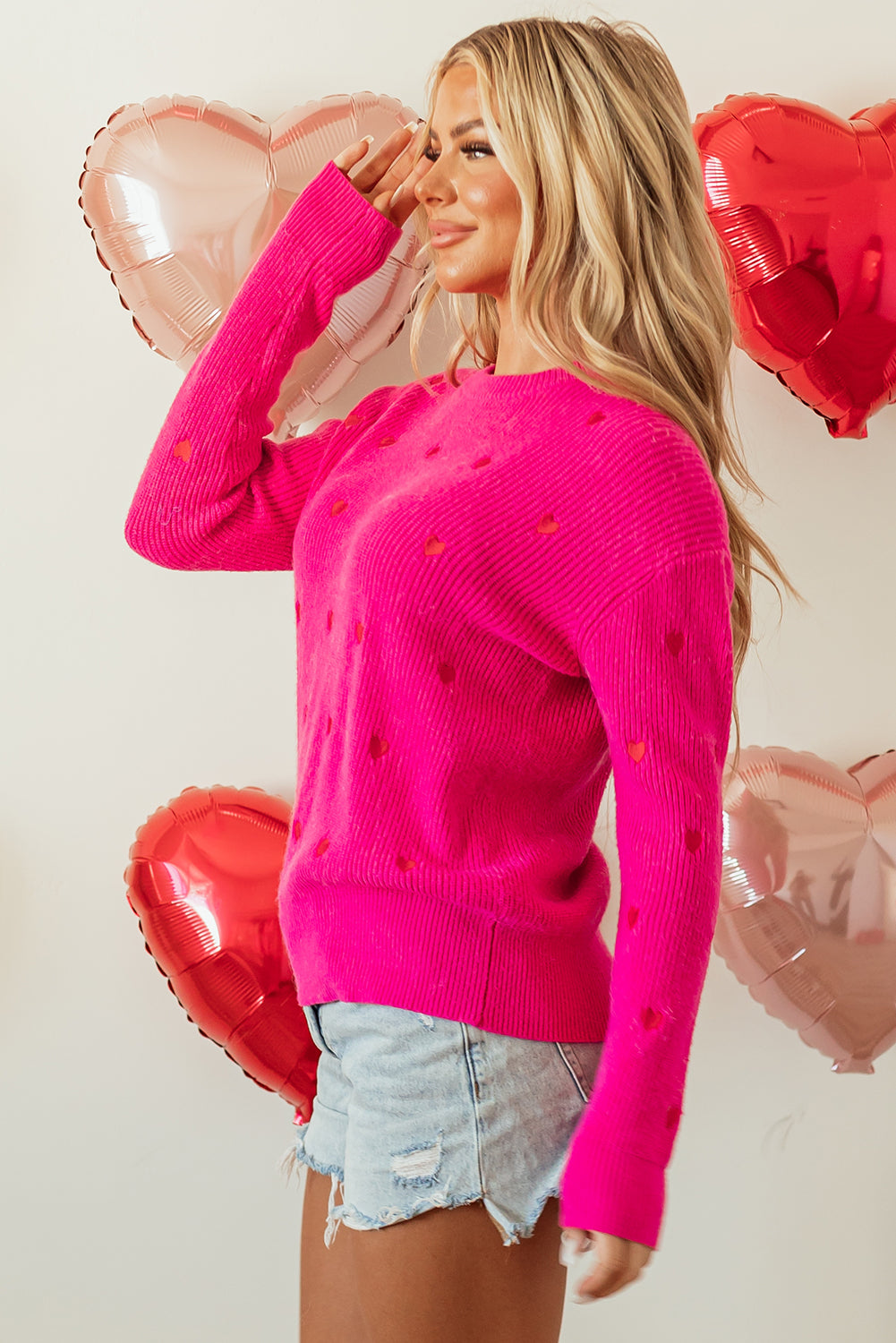 Suéter rojo rosa con cuello redondo, hombros caídos y diseño de corazón.