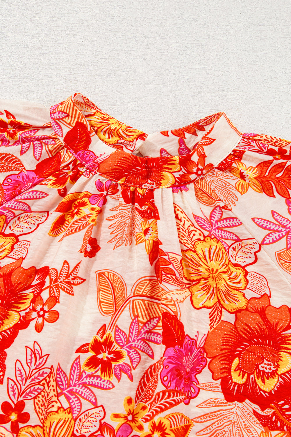 Blusa naranja con estampado floral, botones de perla, abertura tipo lágrima y manga larga abullonada.