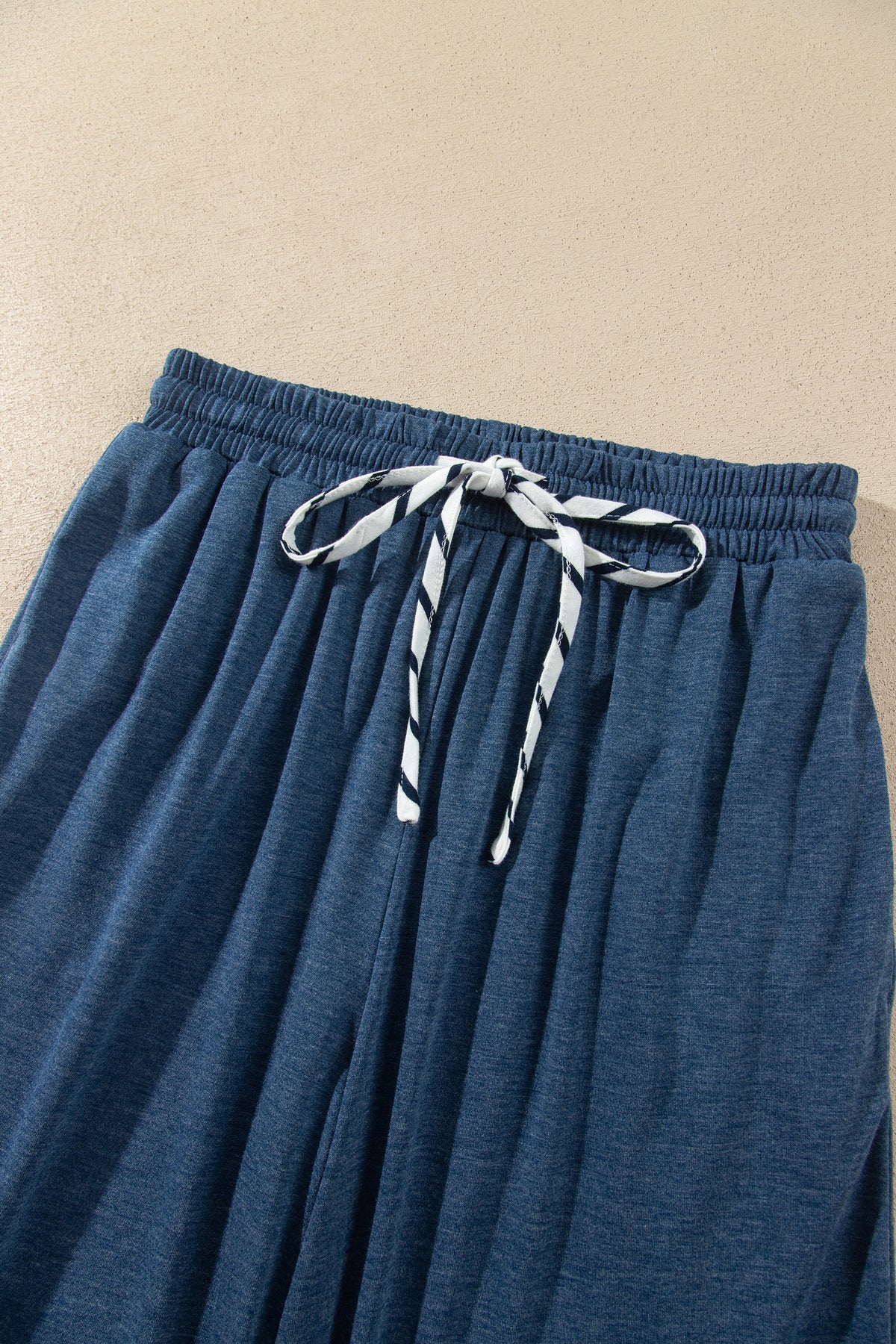 Conjunto de 2 piezas: top de rayas azules con cuello en V y mangas con volantes en contraste, y pantalón con cordón ajustable.