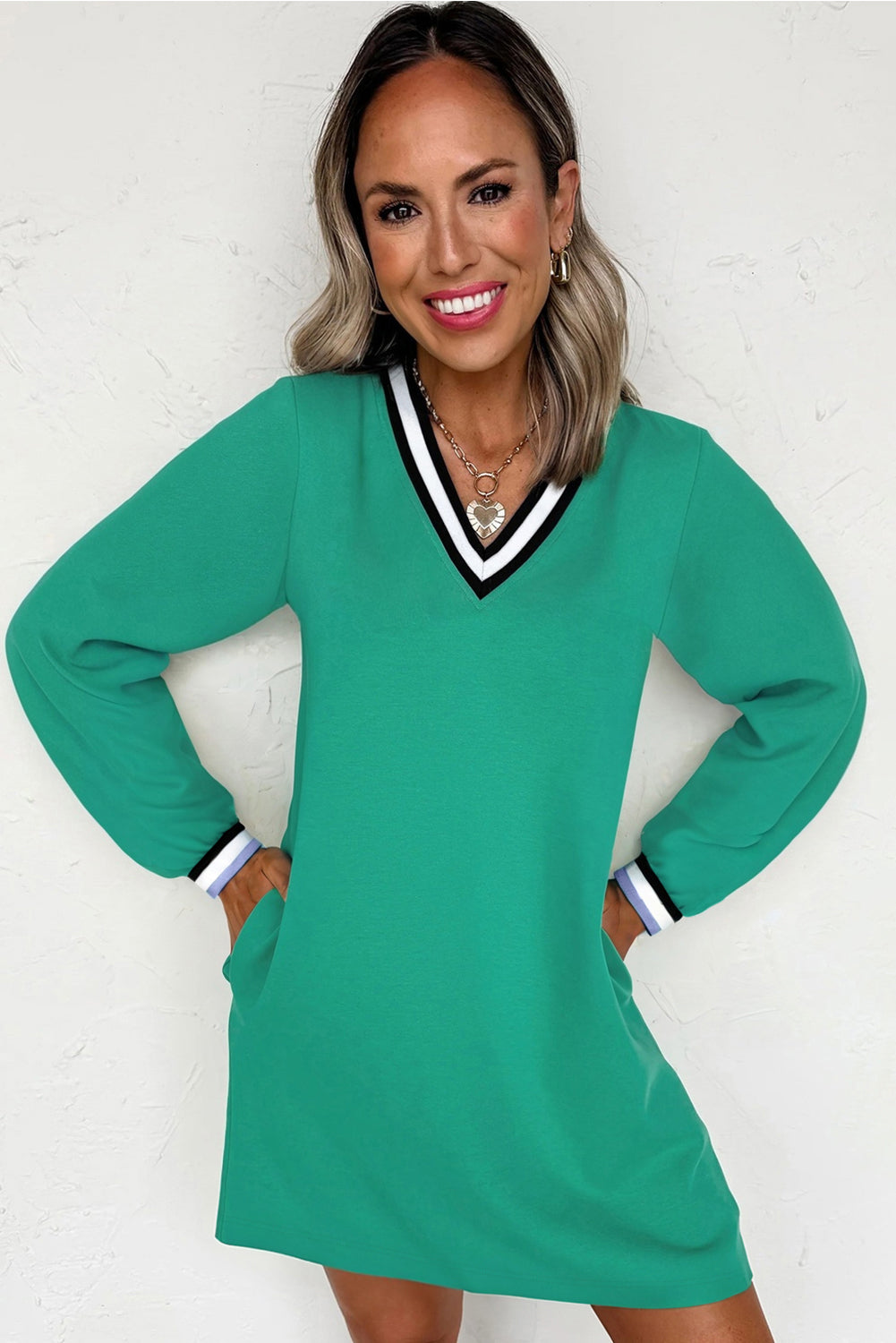Vestido tipo camiseta de manga larga y cuello en V, color verde menta, estilo universitario con rayas en contraste y bolsillos.