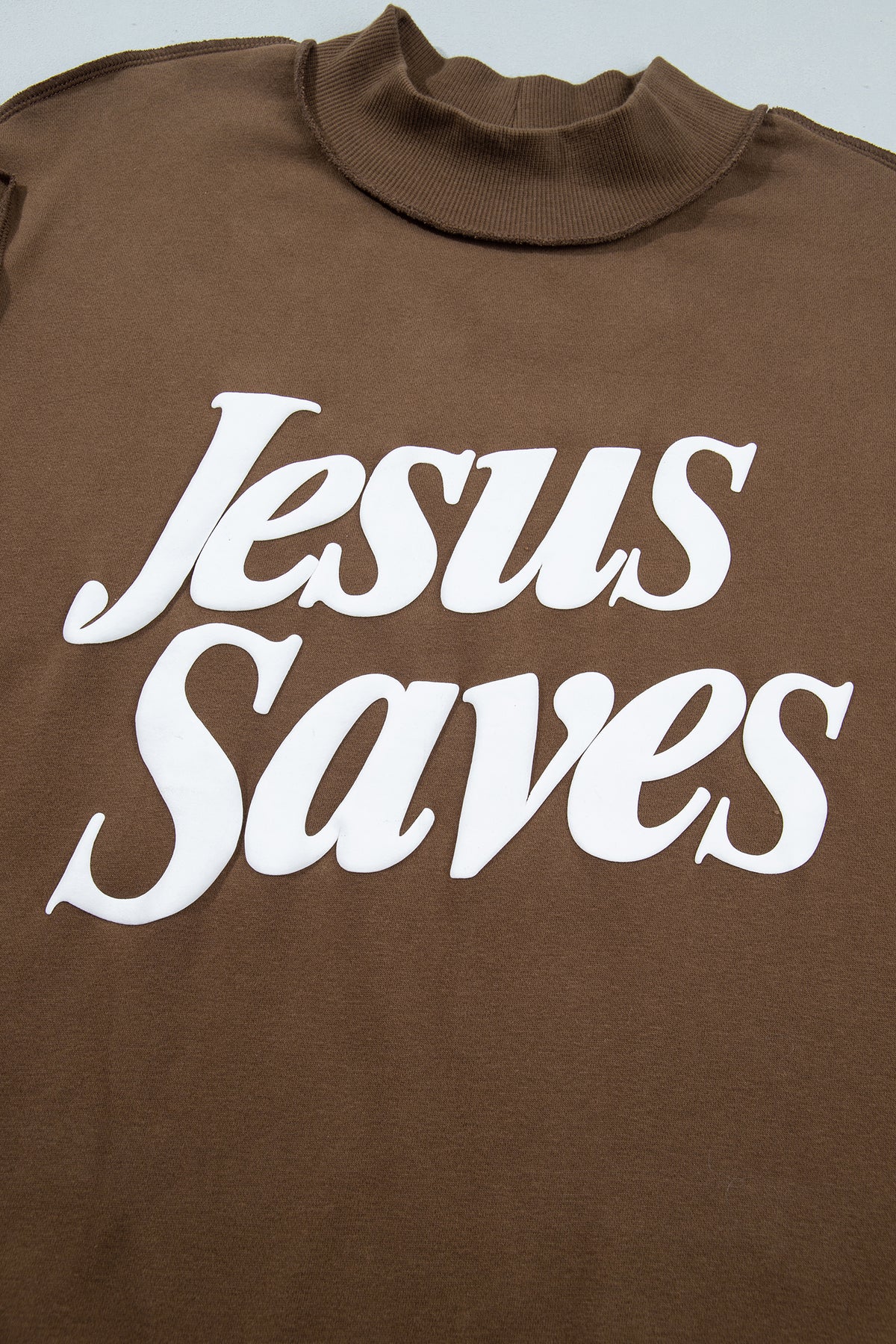 Sudadera holgada de color marrón oscuro con cuello alzado y estampado del eslogan «Jesus Saves»