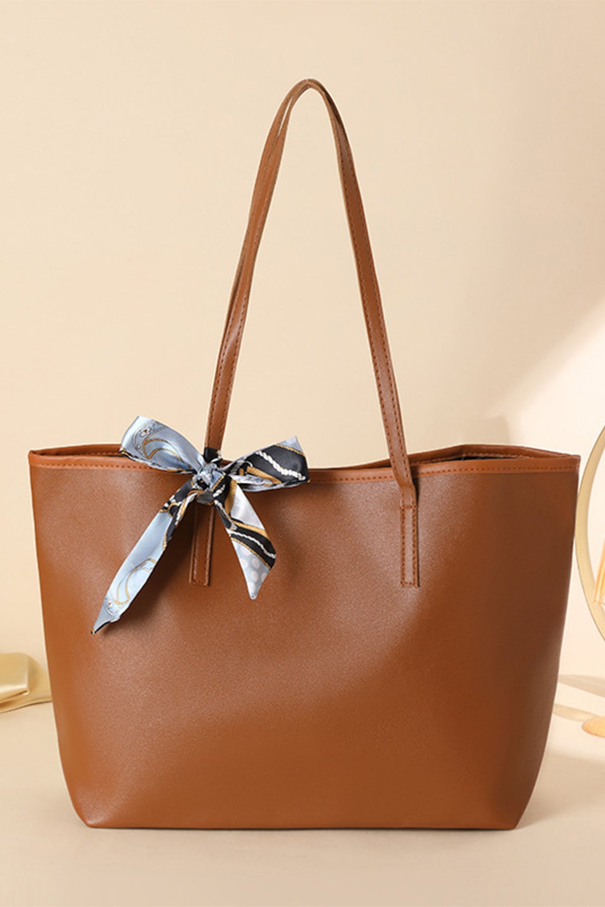Bolso de piel sintética color castaño, de gran capacidad y con detalle de lazo.